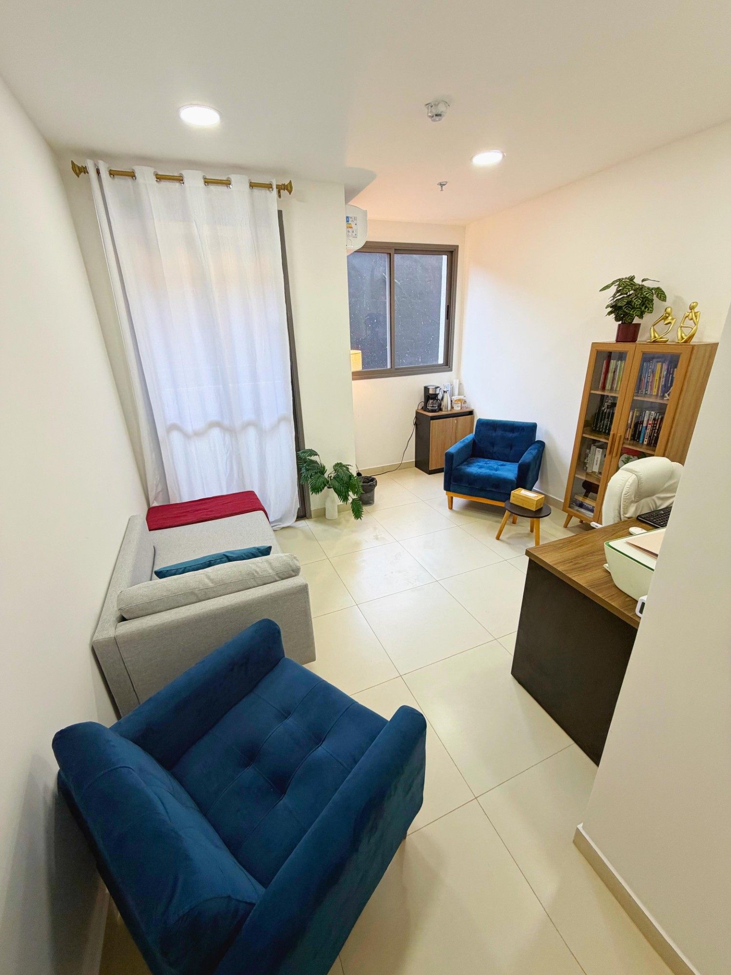 Sala de atendimento da Atenta no Brooklin, com poltronas, sofá, estante e janela